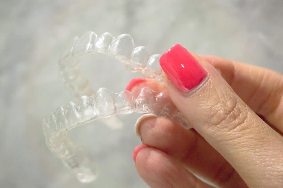 Close-up of a hand holding clear Invisalign aligners.