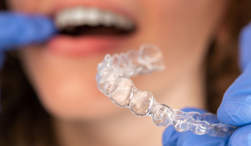 Female patient holding Invisalign as she figures out whether Invisalign works effectively in contrast to ceramic braces.