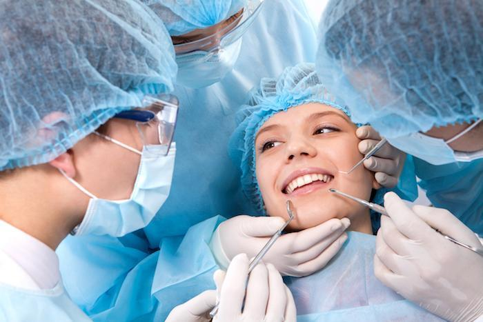 Patient getting dental surgery from the dentist and helpers.